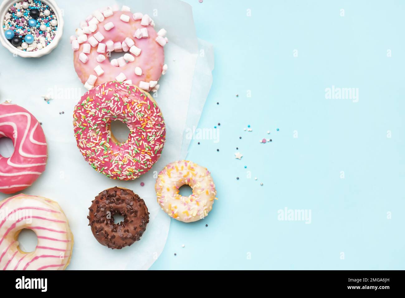 Parchment with different delicious donuts on blue background Stock Photo