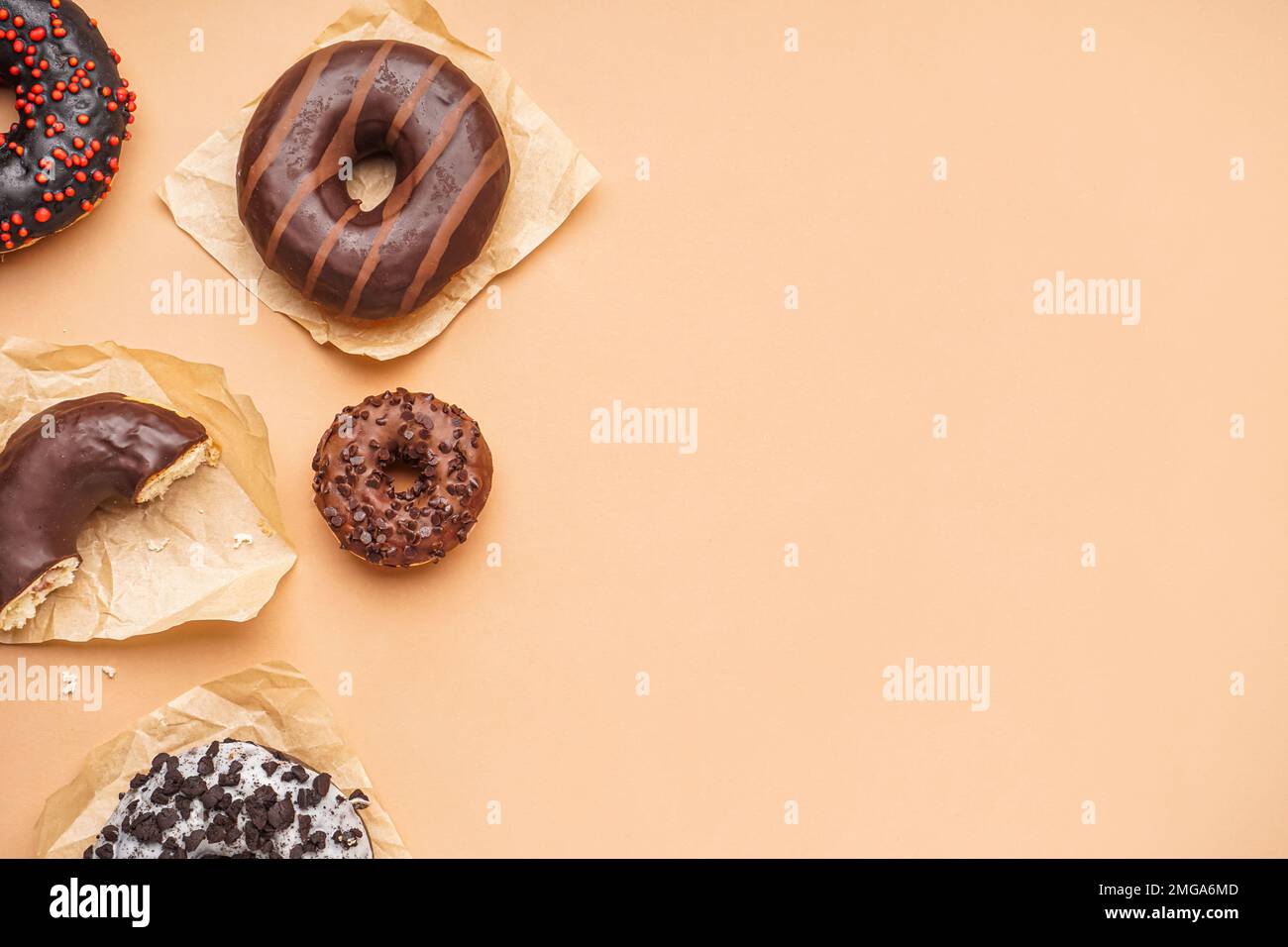 Parchments with different delicious donuts on beige background Stock Photo