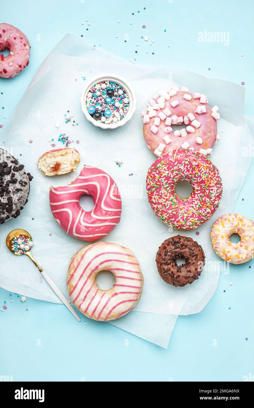 Parchment with different delicious donuts on blue background Stock Photo