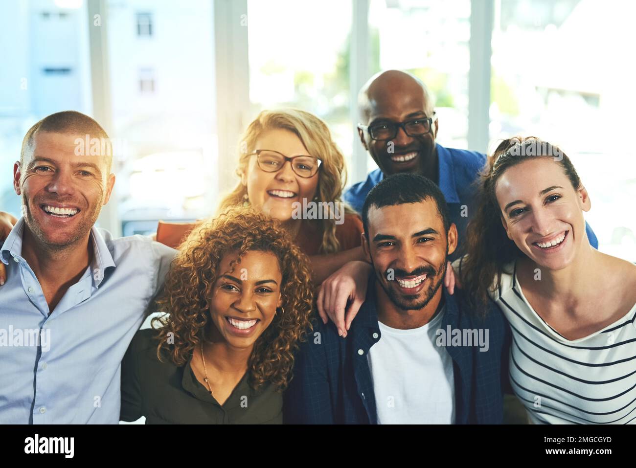 We were made to be friends. a group cheerful friends posing for a portrait while standing inside of a building. Stock Photo
