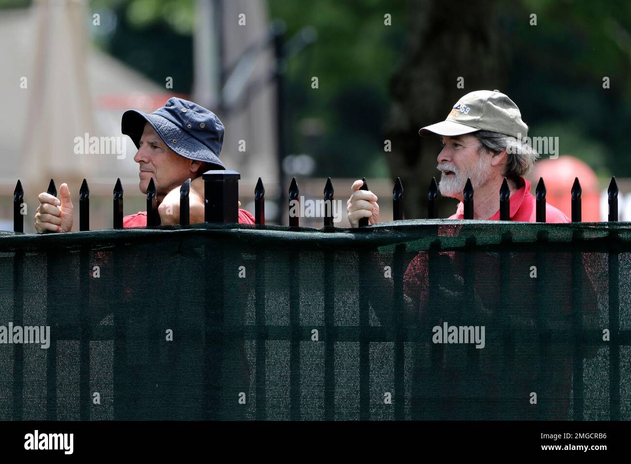 Fans watch Rory McIlroy, of Northern Ireland, play through on the sixth green from behind a fence during the final round of the Travelers Championship golf tournament at TPC River Highlands, Sunday,