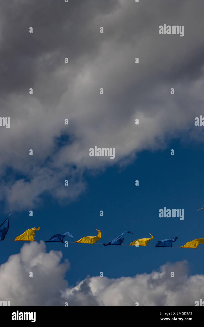 Yellow and blue triangular festival flags on sky background with white ...