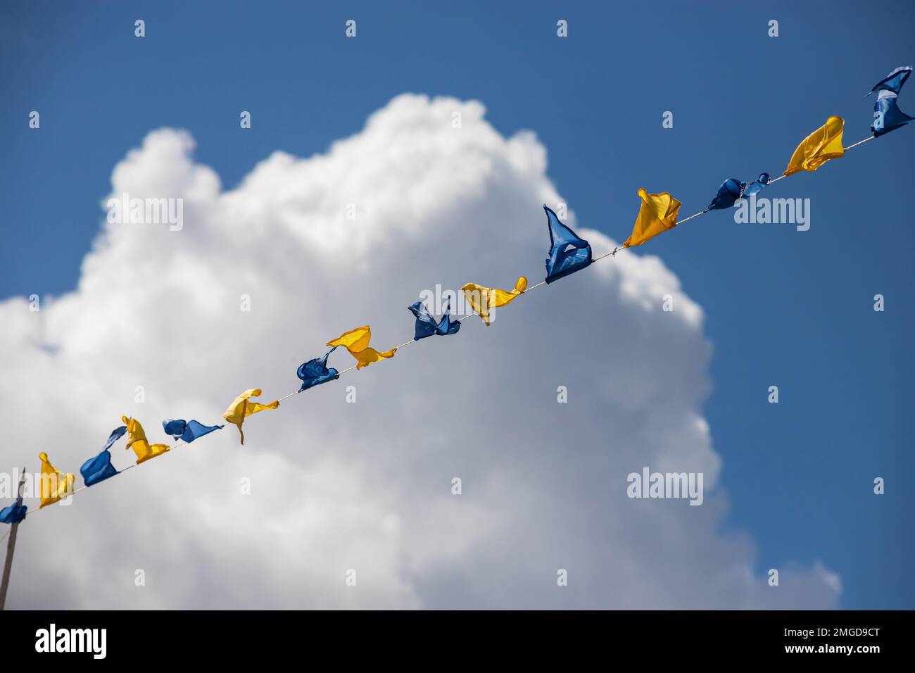 Yellow and blue triangular festival flags on sky background with white ...