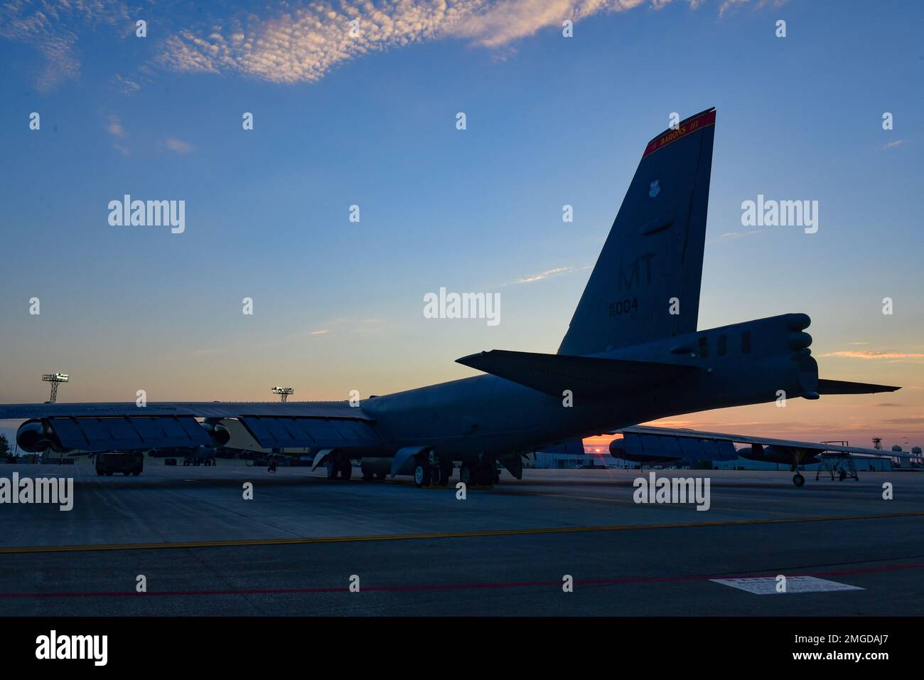 The sun rises over a B-52H Stratofortress parked on the flight line at ...