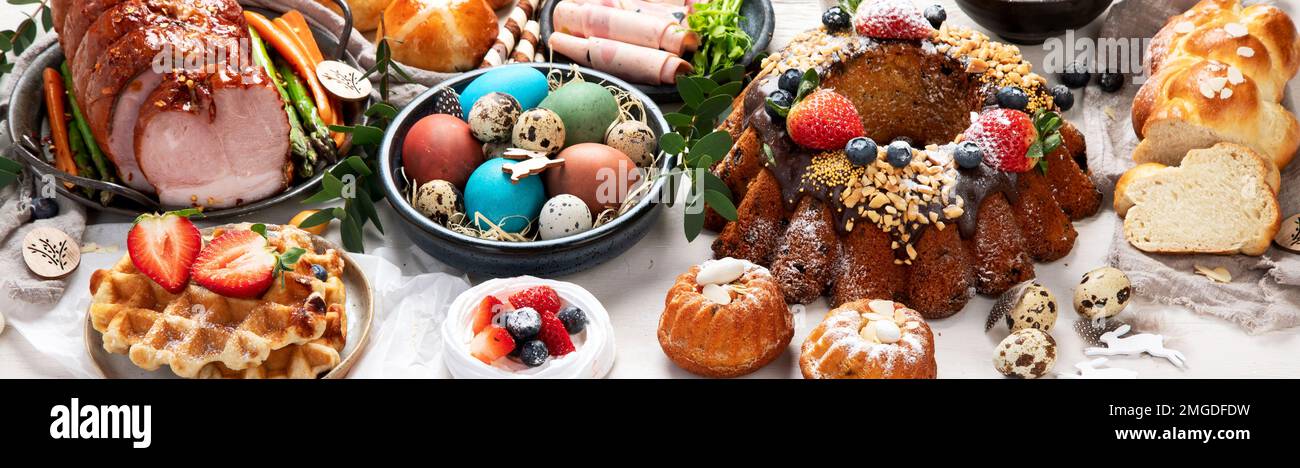 Traditional Easter dinner or brunch with ham, colored eggs, hot cross