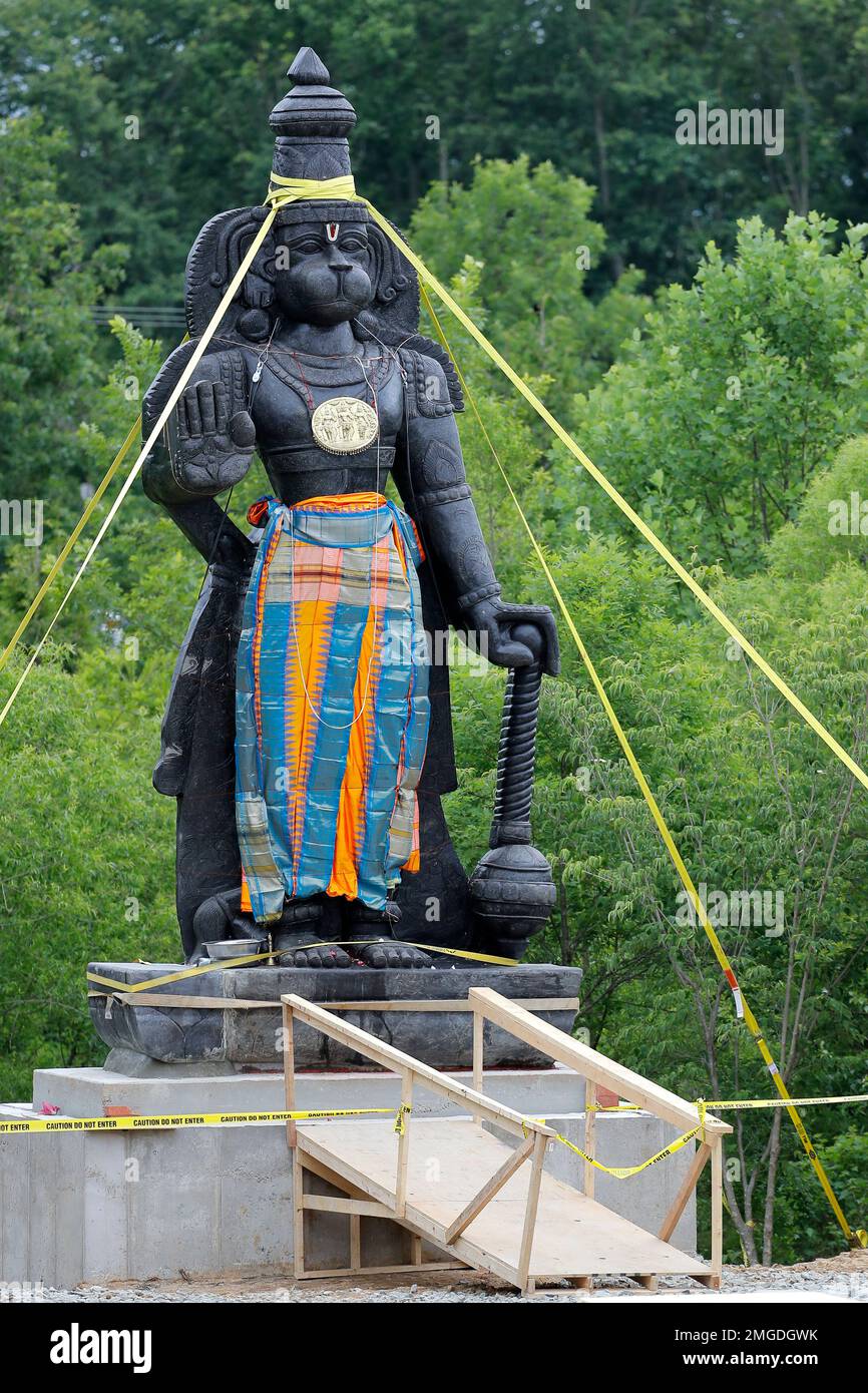 A statue of the Hindu god Hanuman is seen with support straps on the grounds of the Hindu Temple