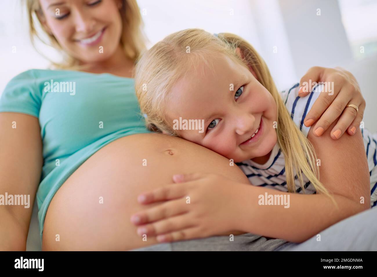 Im going to be the best big sister and babysitter. Portrait of a little girl hugging her mothers pregnant belly at home. Stock Photo