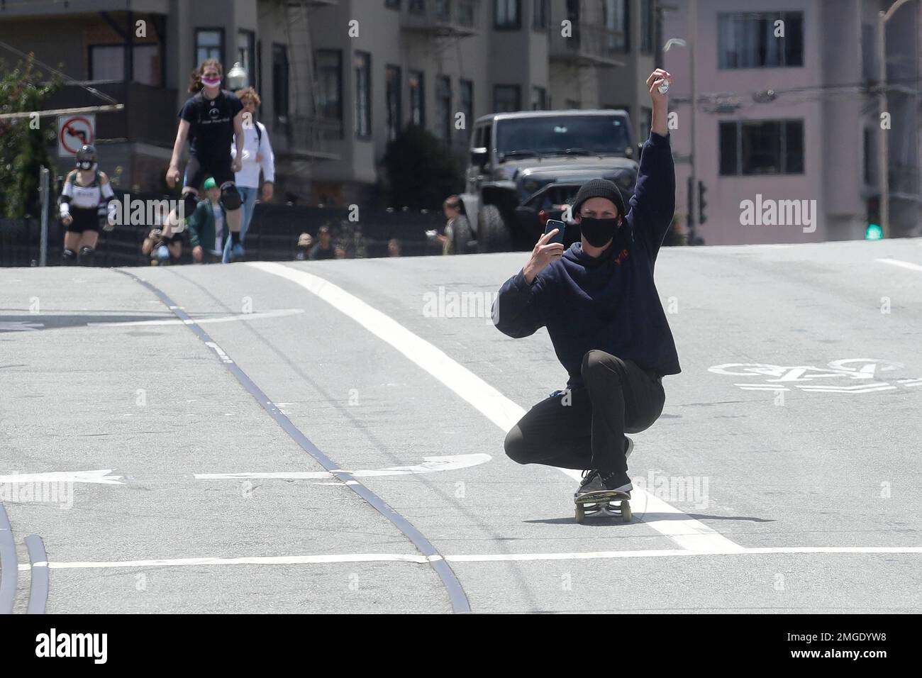 A man raises his fist while riding a skateboard down Market Street in San Francisco, Thursday
