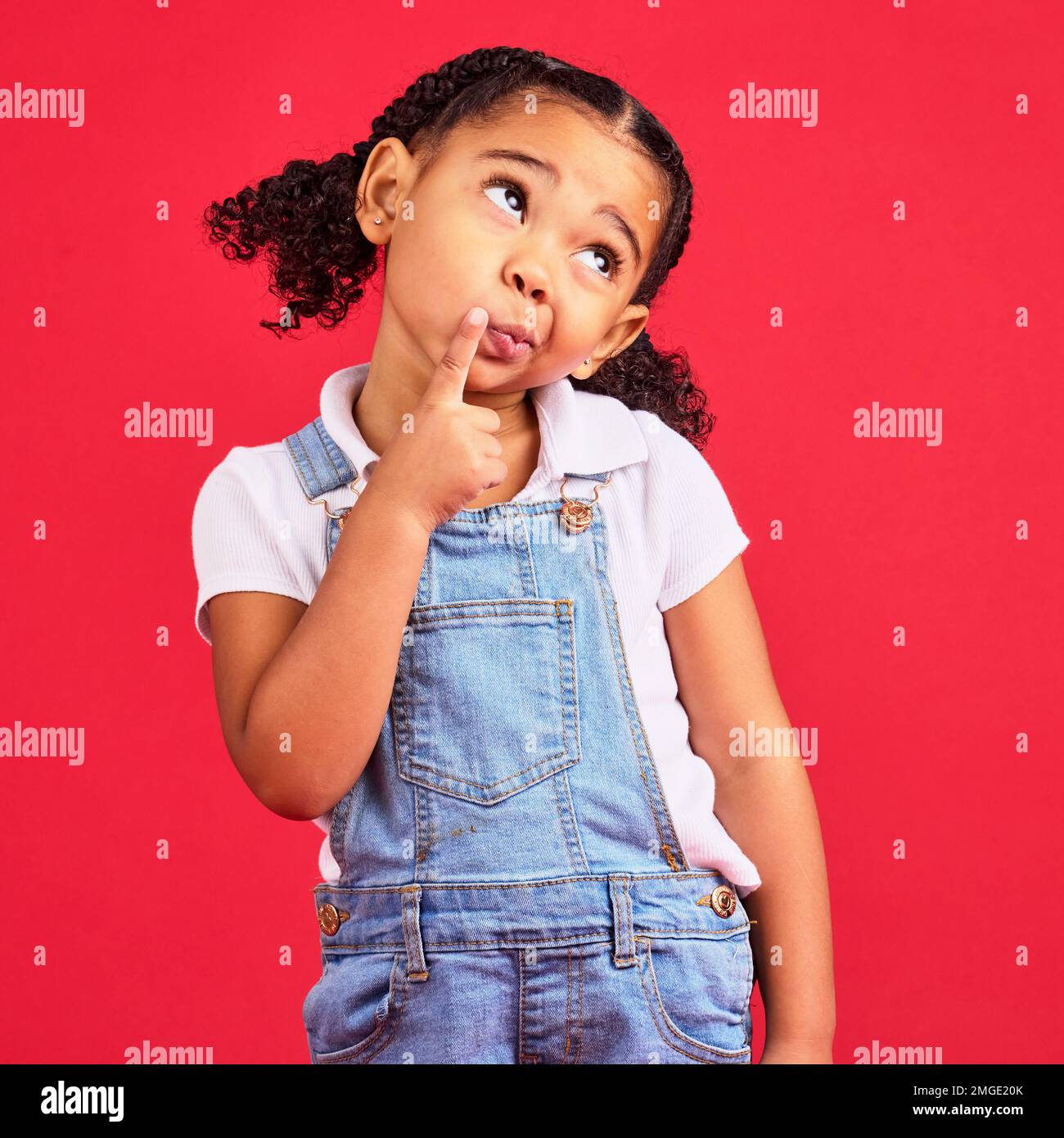 Child, face or thinking finger on chin on isolated red background in games innovation, question or planning vision. Little girl, kid or curious Stock Photo