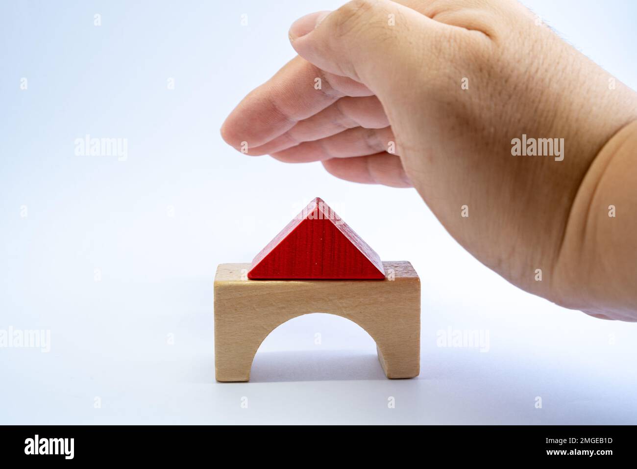 Wood model house covered by man's hand for protection. Property insurance, real estate investment concept. Stock Photo