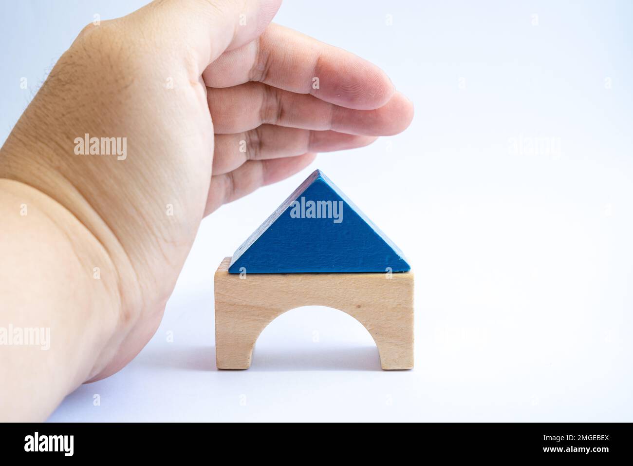 Wood model house covered by man's hand for protection. Property insurance, real estate investment concept. Stock Photo
