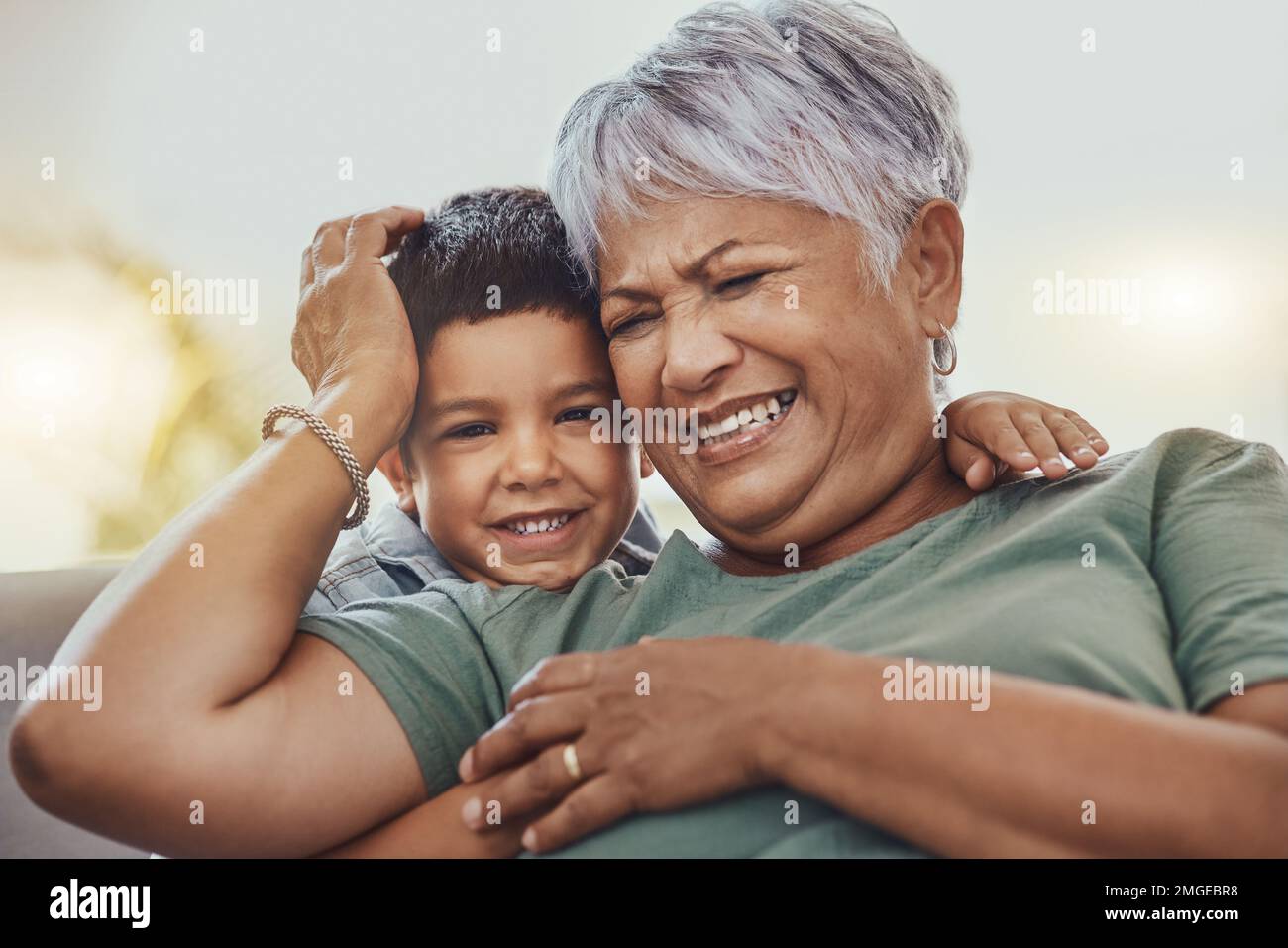 Happy, grandmother and grandchild on a sofa, smile and laugh, love and family while bonding in their home. Relax, grandma and child embrace, funny and Stock Photo