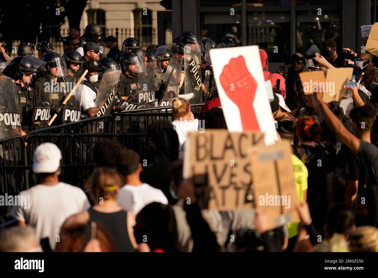 Demonstrators stand in front of police in riot gear as they gather to ...