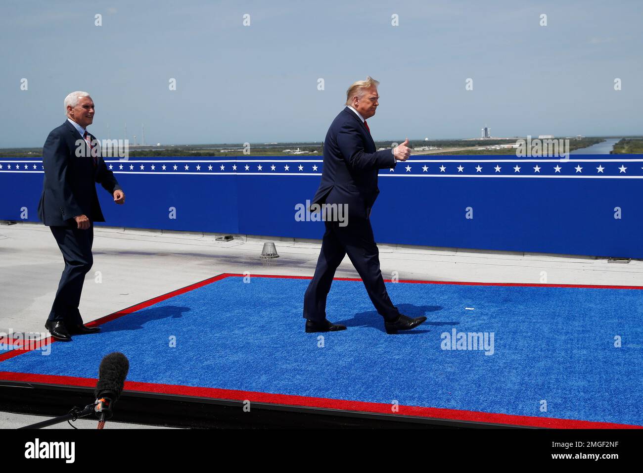President Donald Trump and Vice President Mike Pence, walk on a platform as  a SpaceX Falcon 9, with NASA astronauts Doug Hurley and Bob Behnken in the  Crew Dragon capsule, sits on
