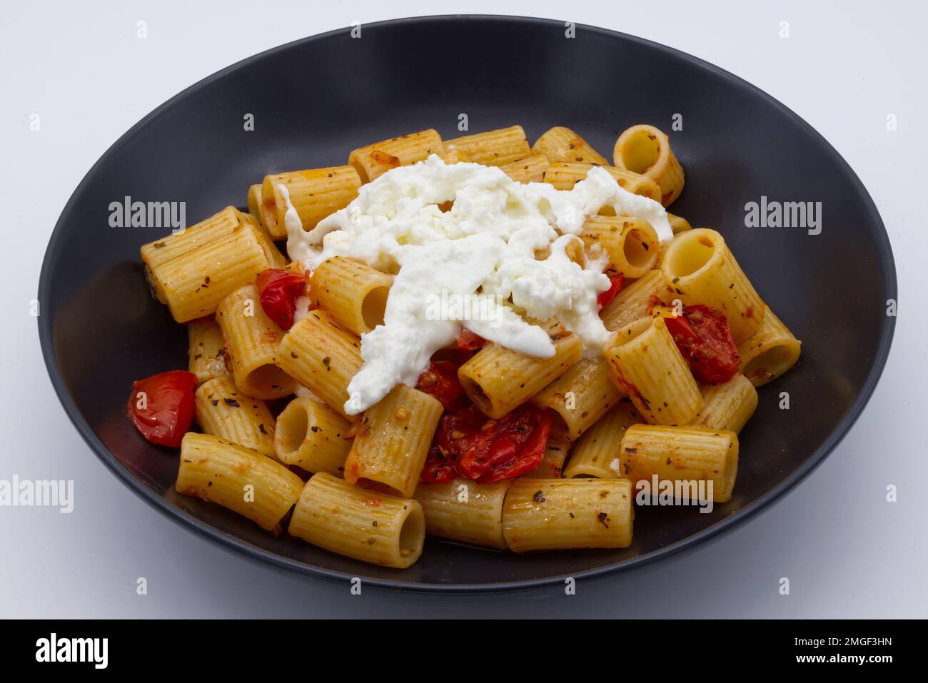 Mezze Maniche Rigate, Italian Pasta, with cherry tomatoes and stracciatella cheese. Stock Photo