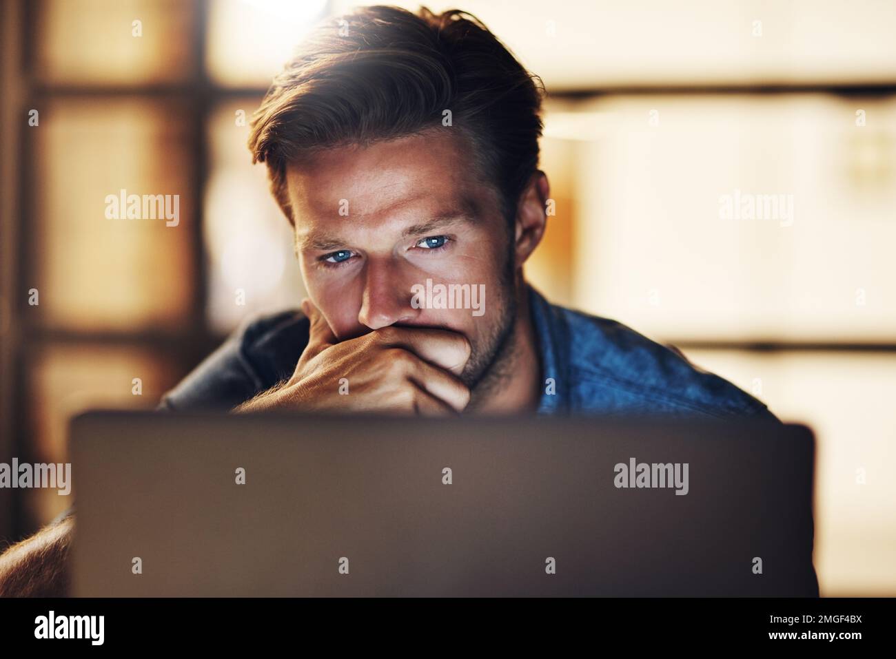 Thinking carefully before making his next move. a handsome young male designer looking thoughtful while working late in his office. Stock Photo