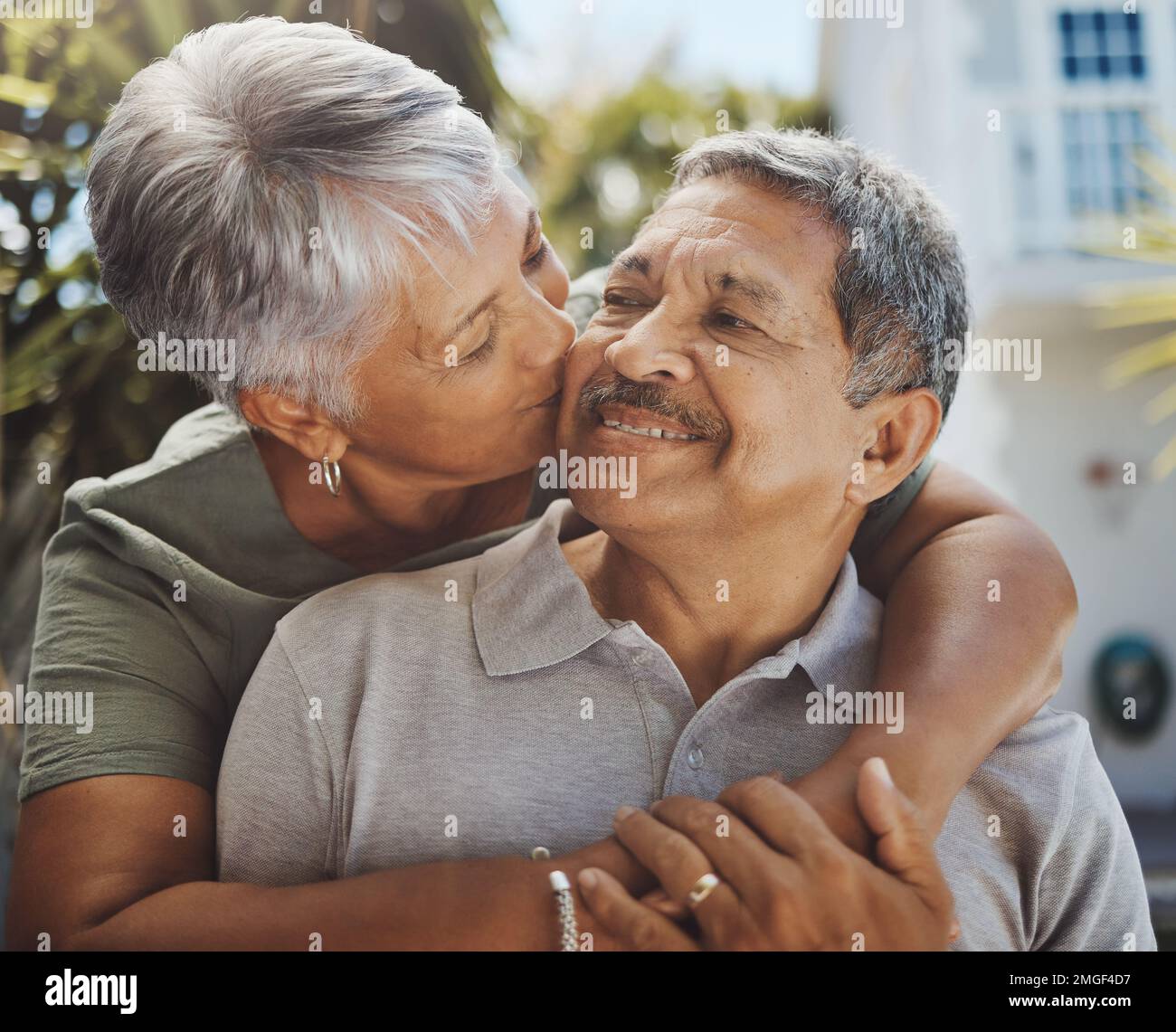 Black senior couple, hug and kiss for love, retirement holiday and happiness outdoor together. African man, woman kissing and happy quality time or Stock Photo