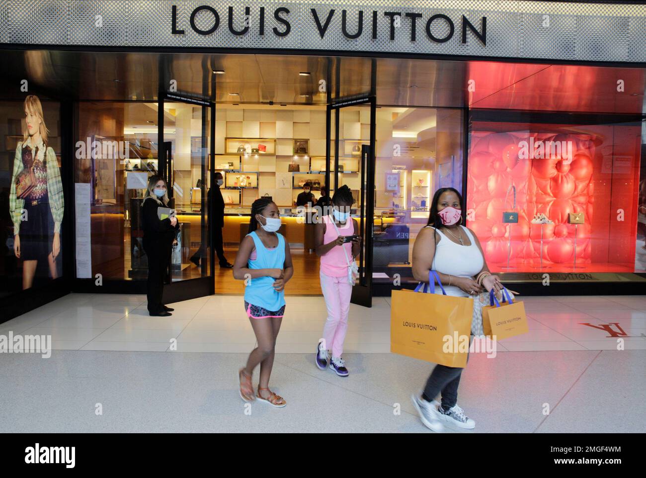 Sharnae Mooreer, right, with daughters, Kimora, 9, left, and Kayla 8, shop  at the Louis Vuitton boutique at the opening of Beverly Center shopping  mall during the coronavirus pandemic in Los Angeles Friday, May 29, 2020.  (AP Photo/Damian Dovarganes