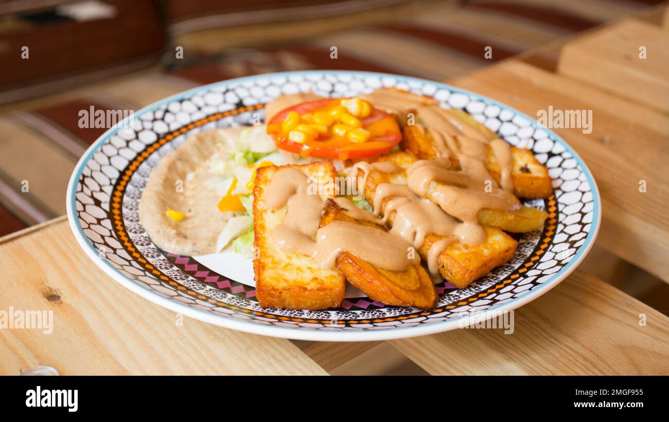 African combo plate with rice, fried cheese, grilled vegetables, peanut sauce and other traditional products. Stock Photo