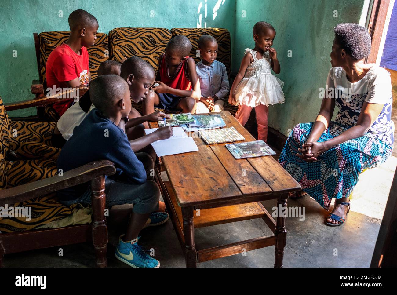 Siblings Rwanda Tresor Ndizihiwe, 12, writes in a book accompanied by his siblings and ...