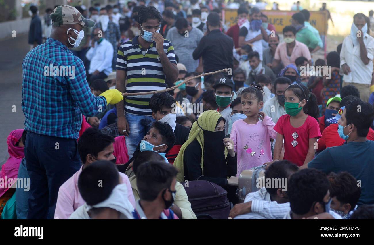 Migrant workers and their families wait to board buses for their onward ...