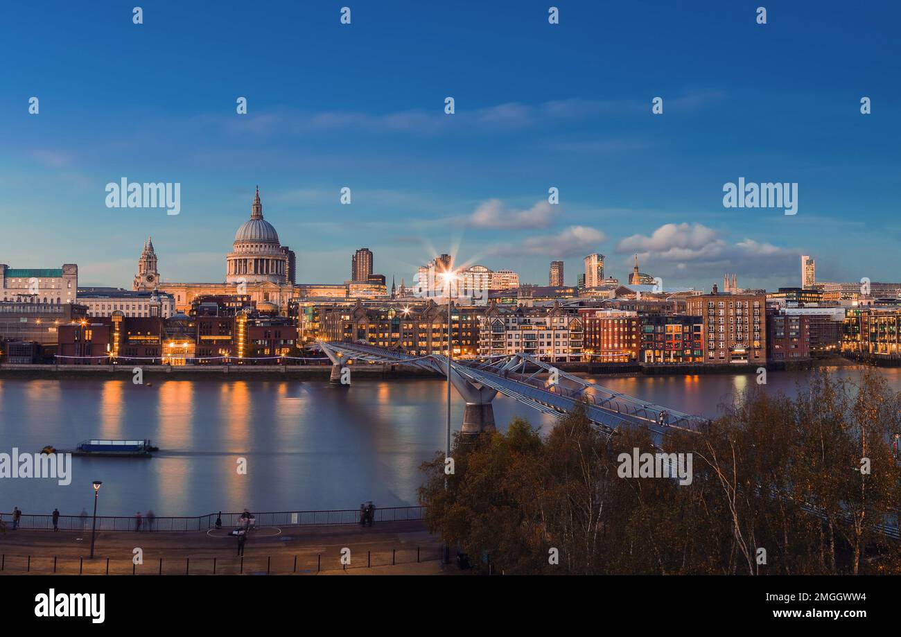 London, United Kingdom - Panoramic view of illuminated Millennium Bridge and St Paul's Cathedral at dusk with clear blue sky Stock Photo