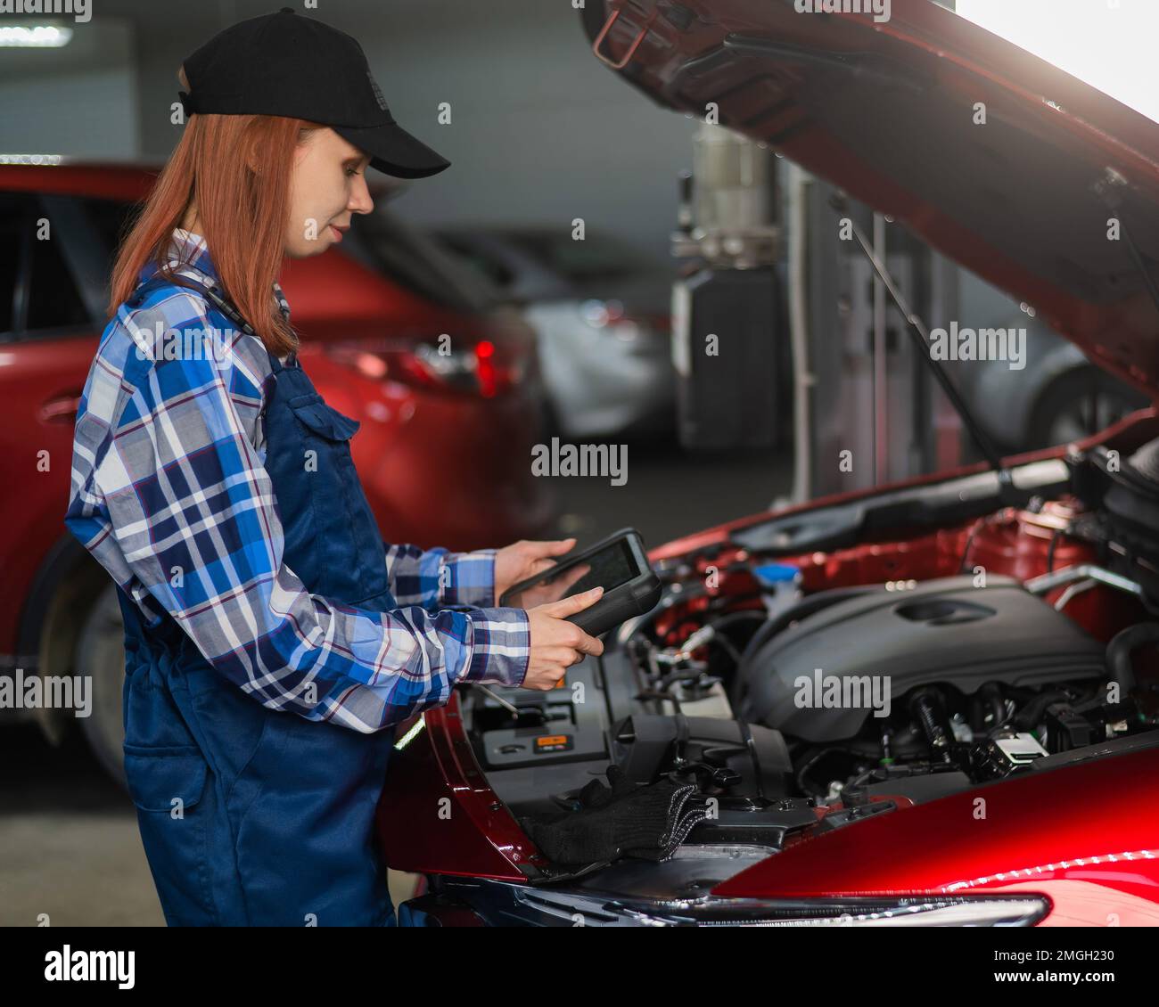 Caucasian female auto mechanic uses a special computer to diagnose