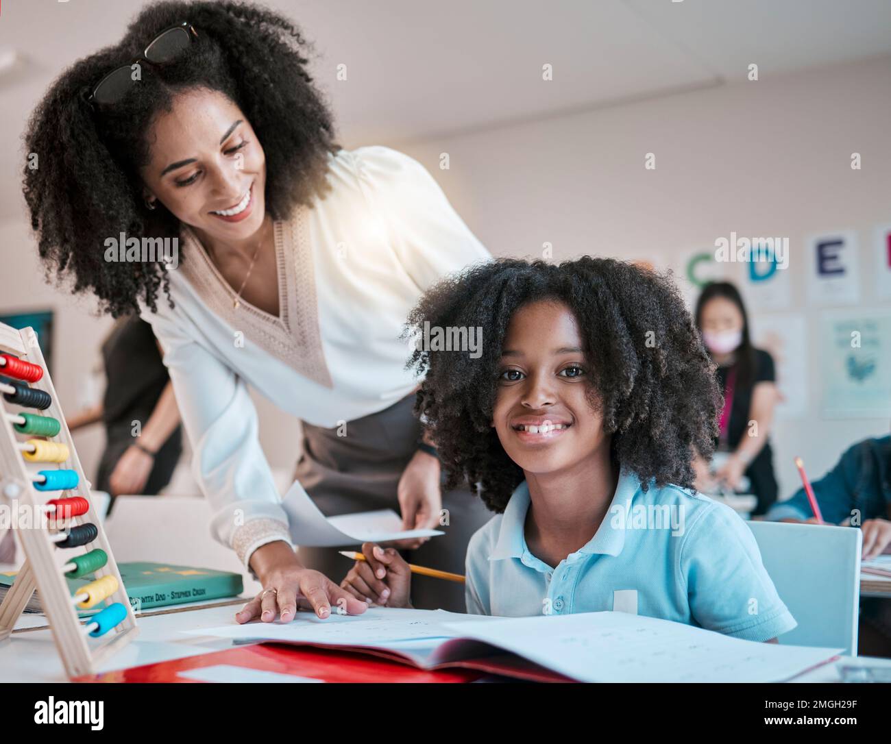 Young child learning maths, happy teacher in classroom with children ...