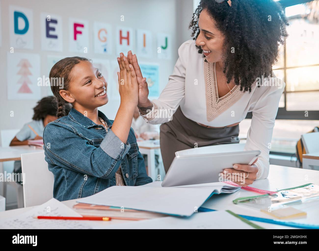 Tablet, high five and teacher with child education, learning and support, achievement and classroom goal. Mentor, black woman or person and girl in Stock Photo