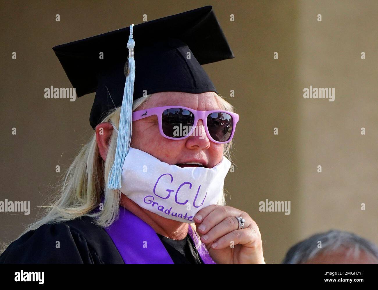 Linda White stands in her driveway in her cap, gown and a face 