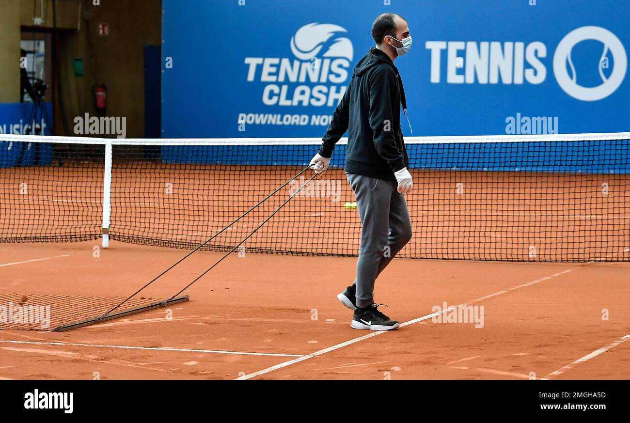 A helper with a face mask prepares the court at a protennis tournament