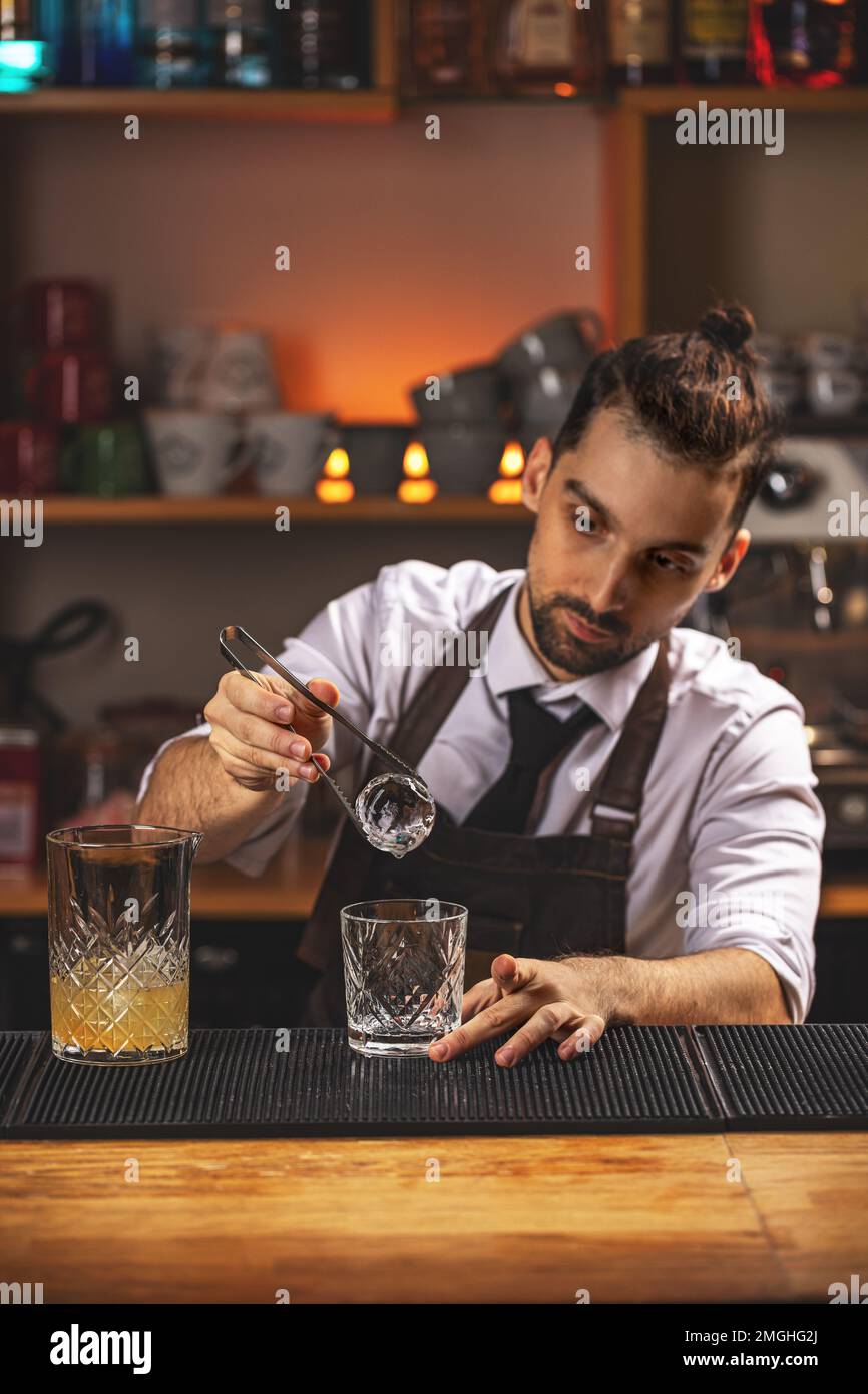 https://c8.alamy.com/comp/2MGHG2J/barman-is-putting-ice-ball-into-cocktail-glass-2MGHG2J.jpg