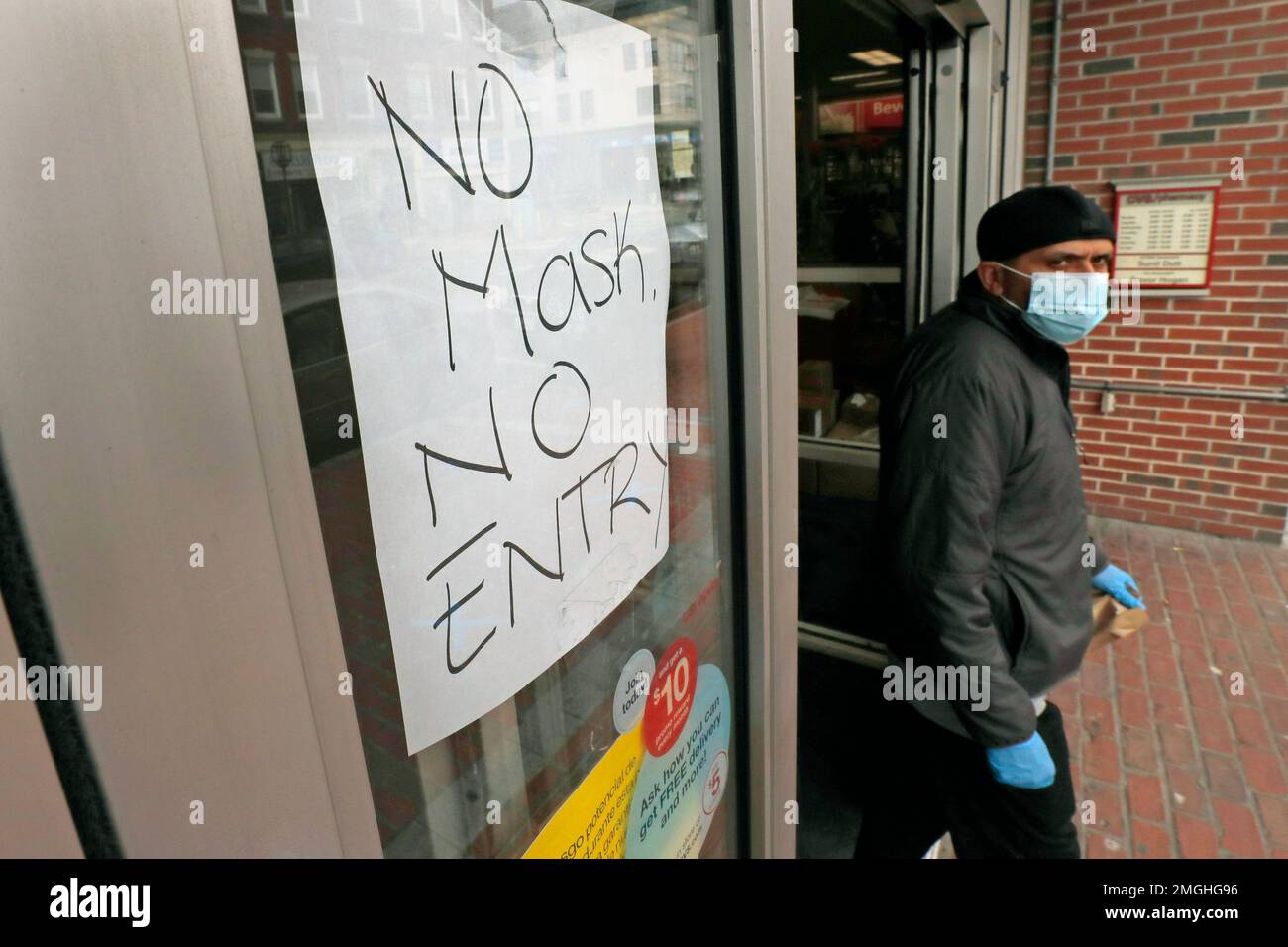 A masked shopper walks past a sign taped to the front door of a CVS ...