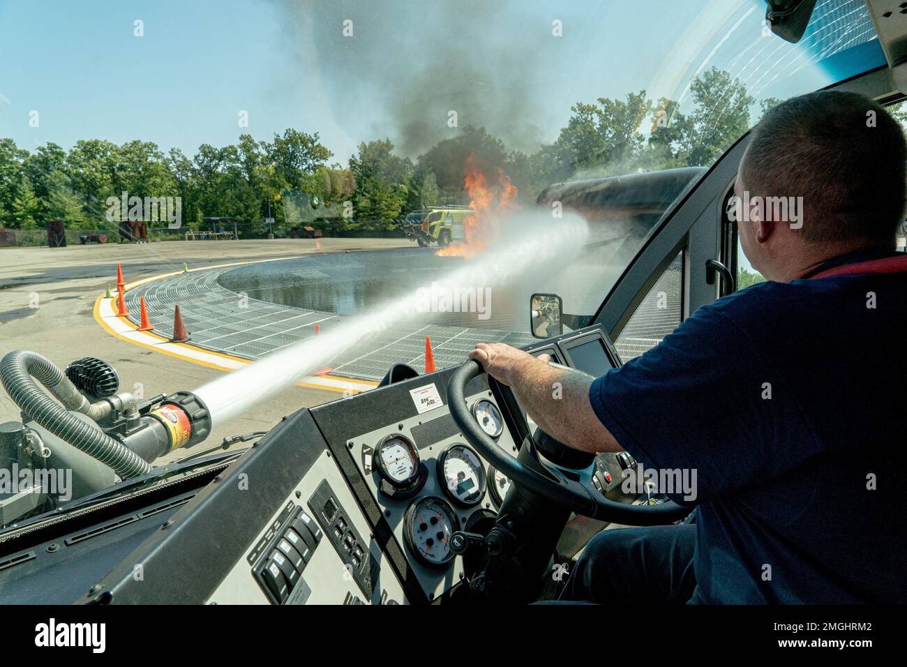 Firefighter John Russum from the 914th Air Refueling Wing's Fire Emergency Services controls a water cannon as he drives a fire truck towards a simulated Boeing 737 crash during training in Rochester, New York, August 24, 2022. Training for an aircraft fire enhances readiness of our firefighters by giving them hands on experience on how to suppress and ultimately put out the flames as quickly as possible to prevent further damage or injuries. Stock Photo