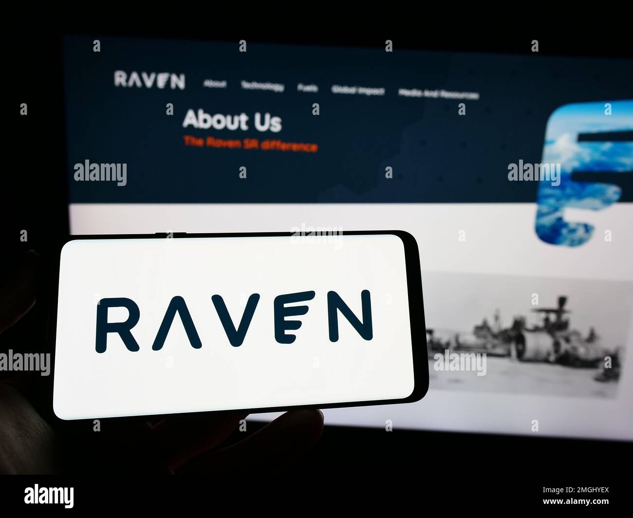 Person holding mobile phone with logo of American renewable fuels company Raven SR Inc. on screen in front of web page. Focus on phone display. Stock Photo