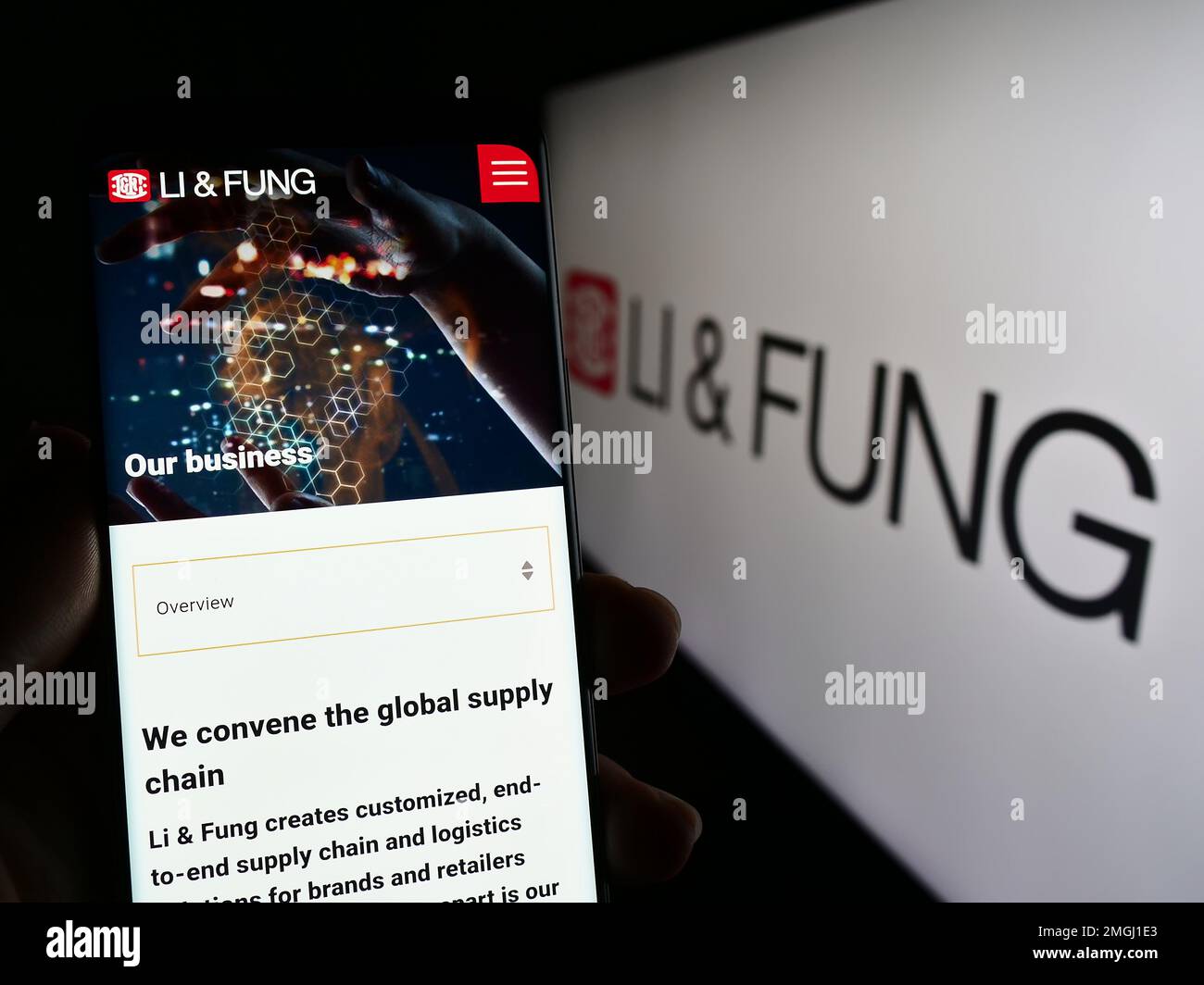 Person holding cellphone with webpage of supply chain management company Li Fung Limited on screen with logo. Focus on center of phone display. Stock Photo