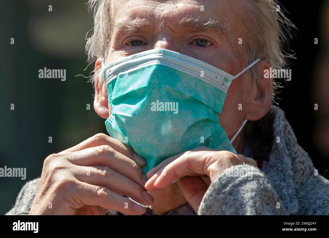 Nursing home resident Siegfried Bilz fixes his face mask while handing