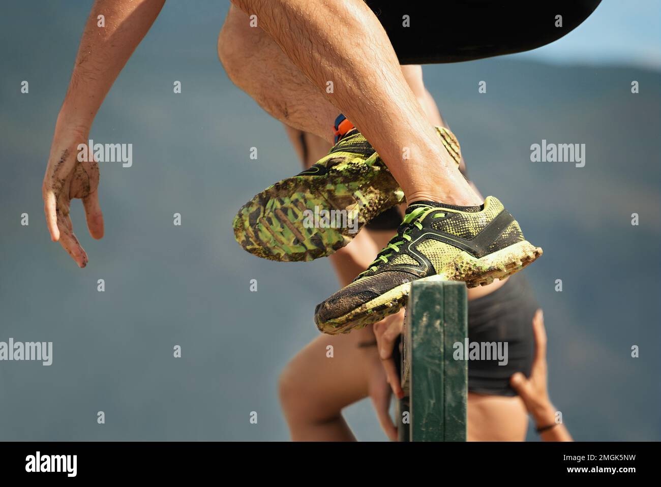 Mud race runners,participants jumps over obstacles,in the background help the woman to overcome the obstacle Stock Photo