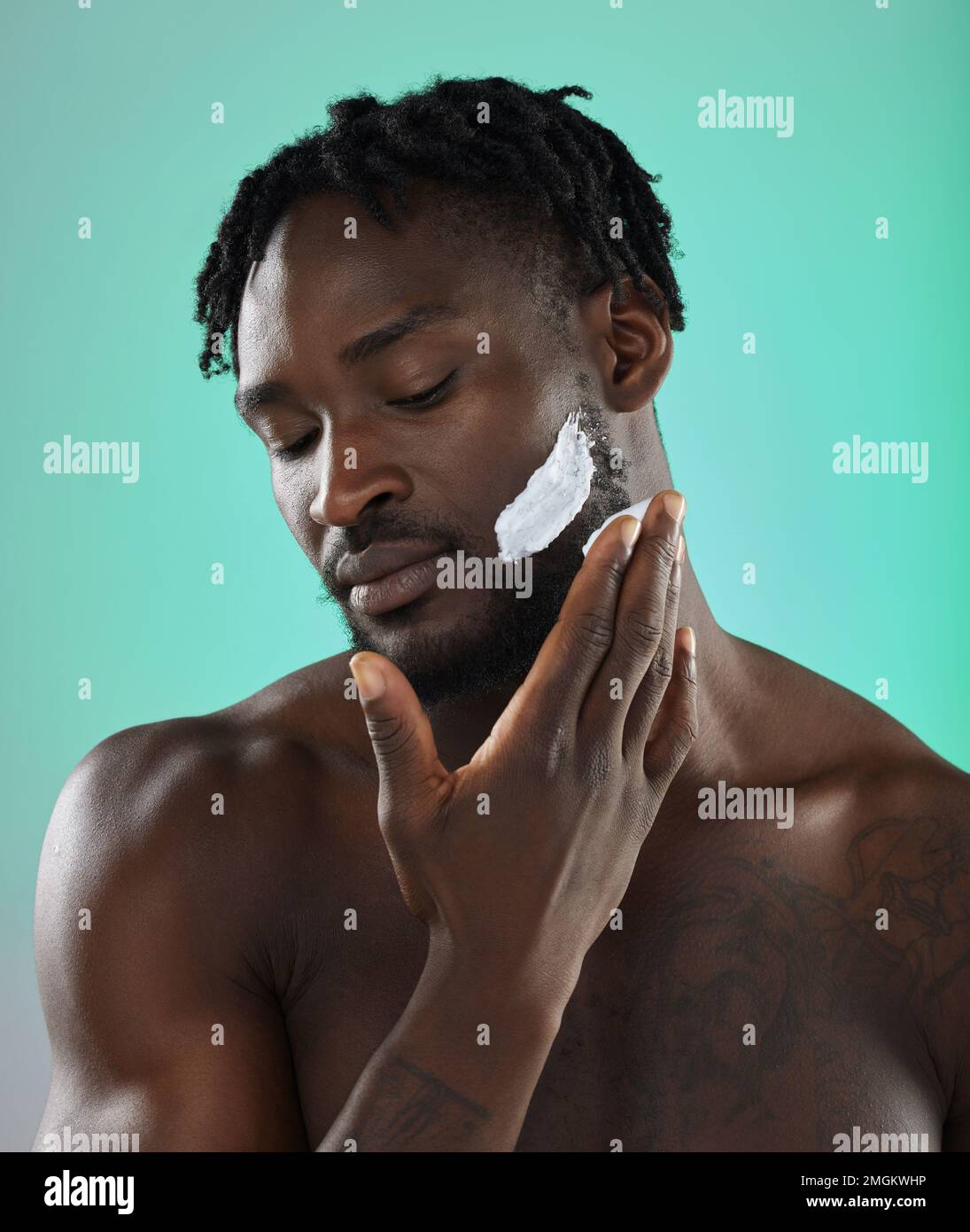 Black man with shaving cream, skincare product on face in studio