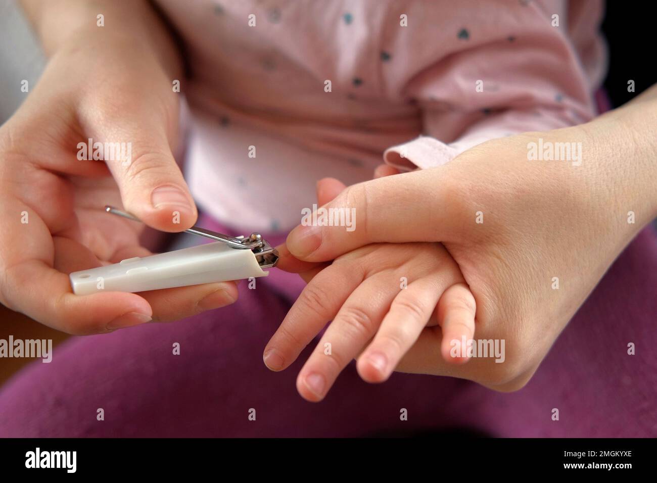 Mother use Nail Trimmer with baby hand. Mom cutting tiny fingernails. Baby care concept. How to successfully clip your baby's nails. Closeup. Newborn Stock Photo