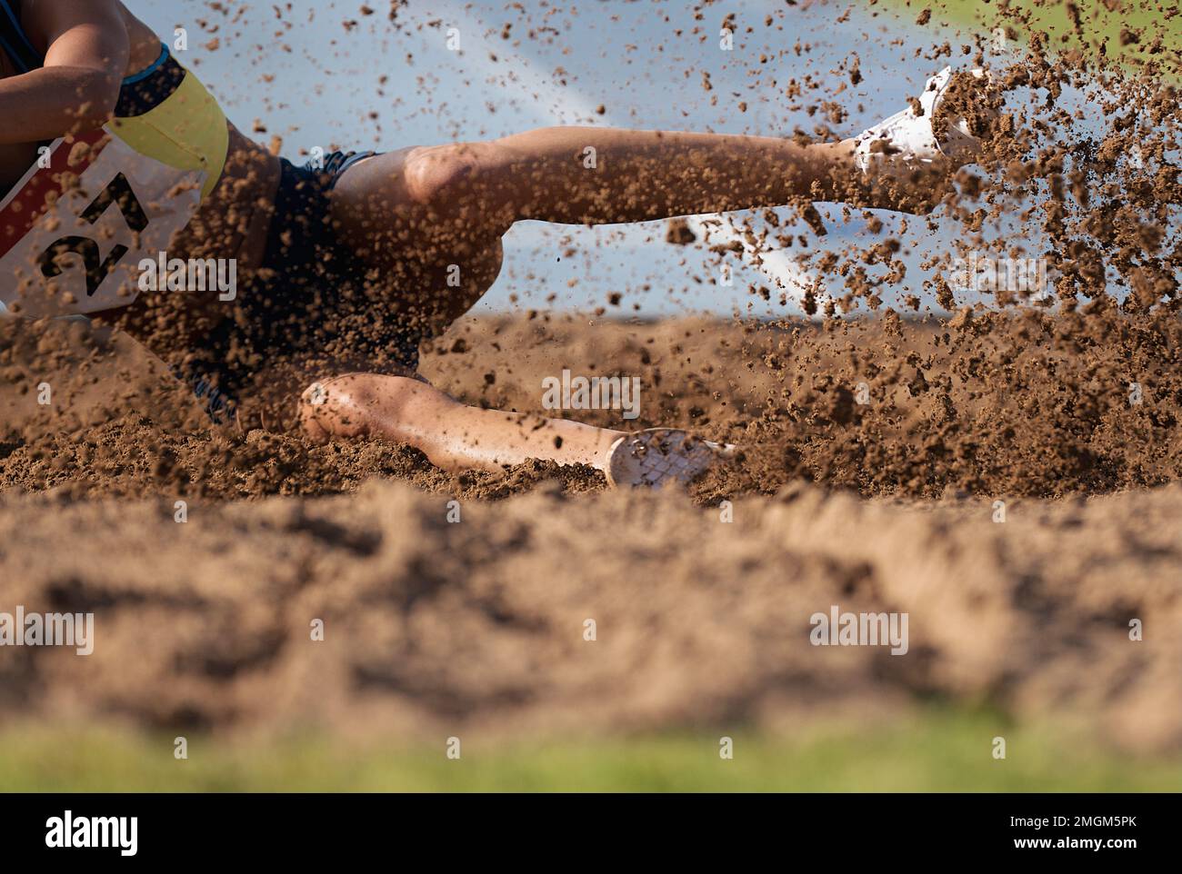 Woman athlete jumping long jump landing in sandpit Stock Photo - Alamy