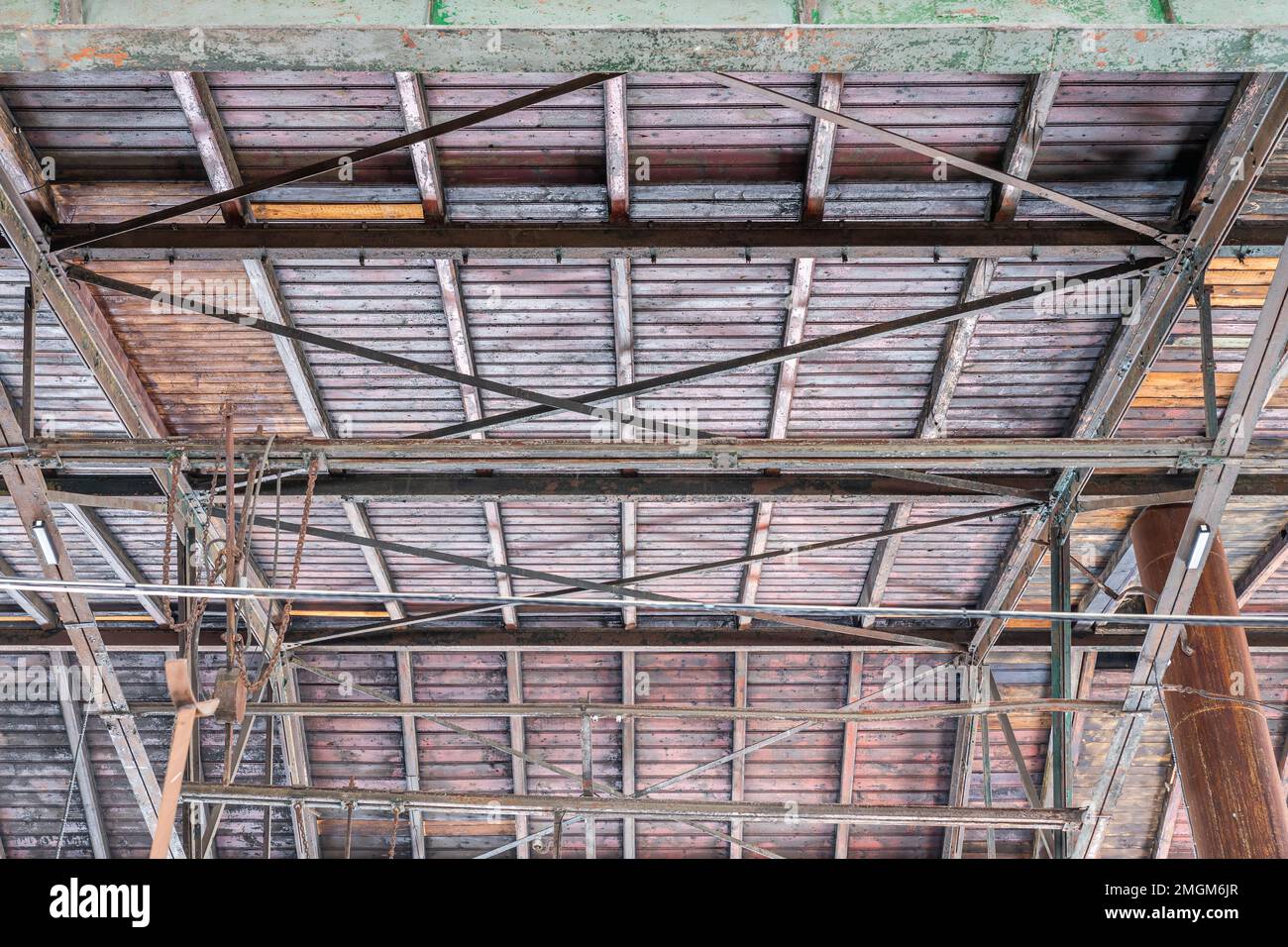 Gable roof truss of a large, vintage factory hall. Roofing construction (sheathing) made of wooden planks. Industrial interior. Stock Photo