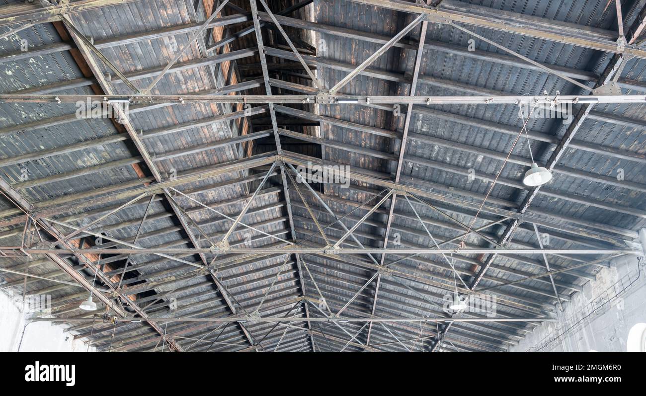 Gable roof truss of a large, vintage factory hall. Roofing construction (sheathing) made of wooden planks. Industrial interior. Stock Photo