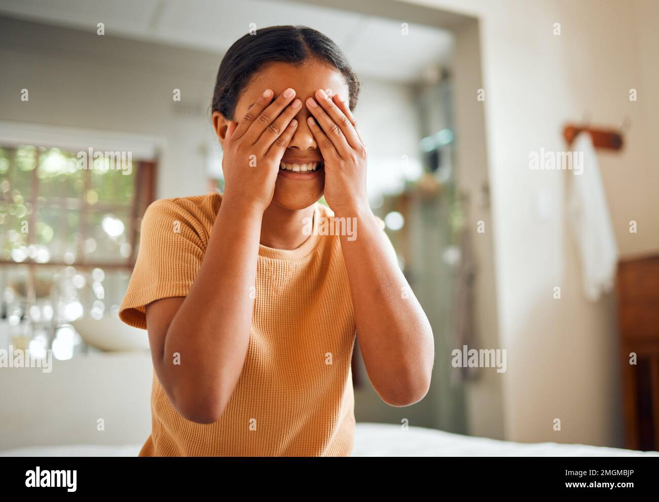 Cover eyes, grooming and child in the bathroom for facial cleaning, wellness and hygiene. Health, happy and girl hiding her face for beauty, washing Stock Photo
