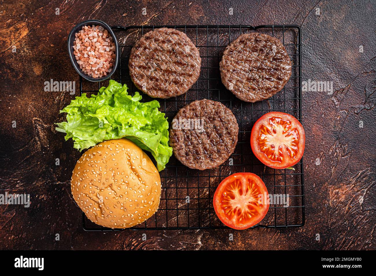 Grilled hamburger patties with tomatoes and seasonings on kitchen table