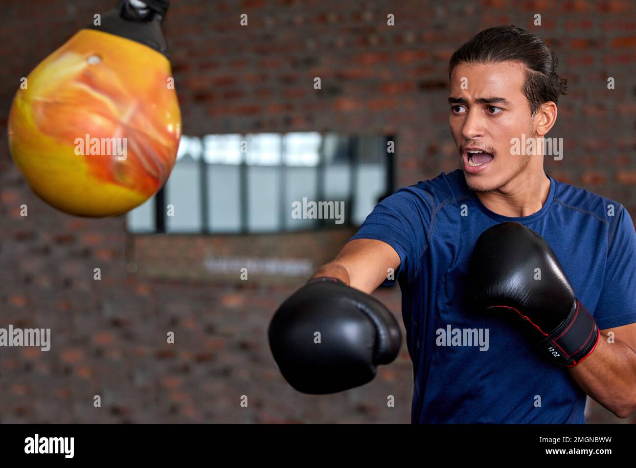 Gym fitness and boxer man punch for sports workout, training and athlete practice with equipment. Energy, focus and power of young martial arts Stock Photo