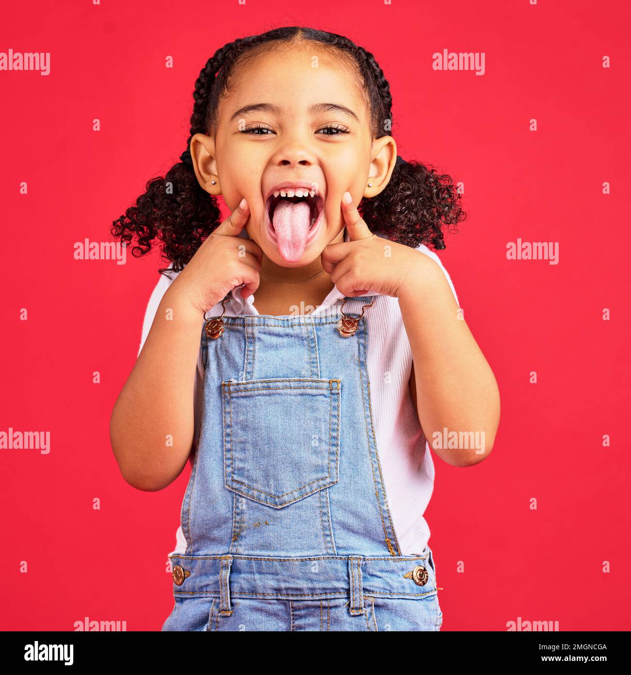 Little girl, portrait and tongue out on isolated red background in goofy, silly games and playful facial expression. Happy, kid and child with funny Stock Photo