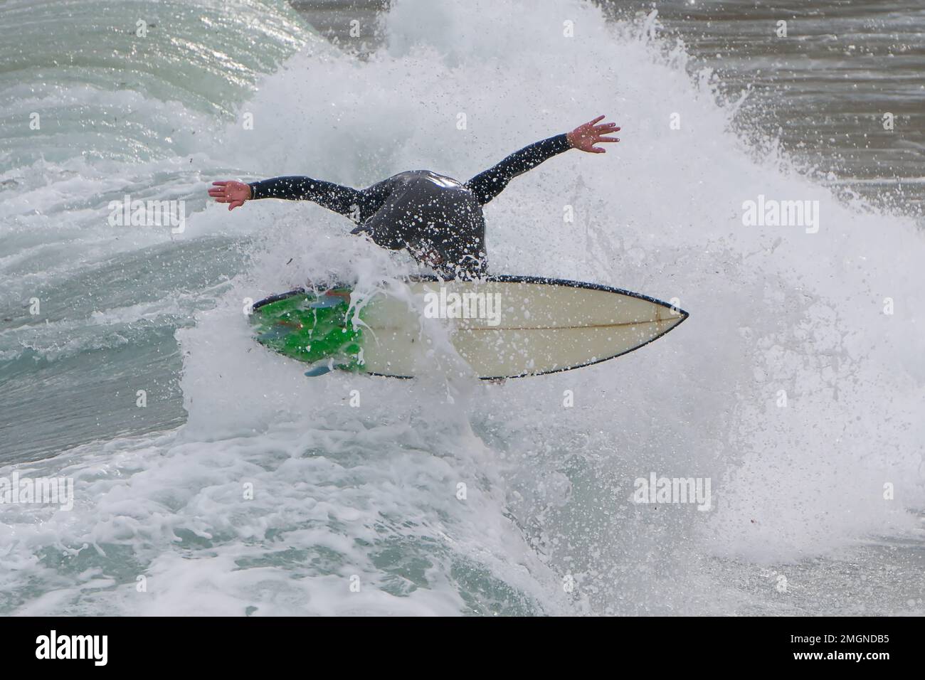 Surfer falling off board as waves crash in a wipeout Stock Photo