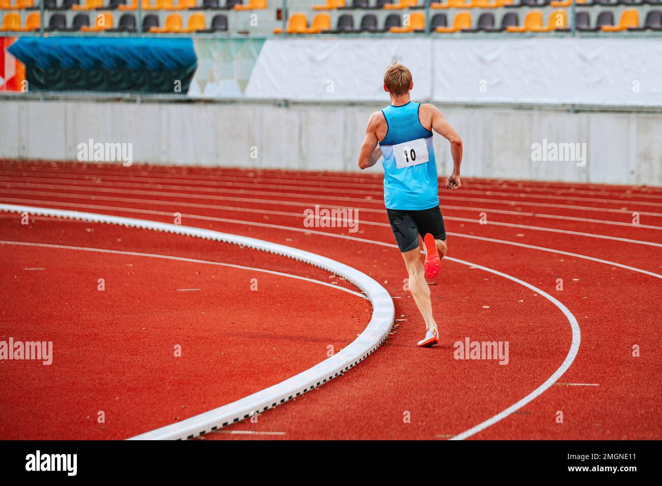 Intense male athlete at the peak of competition in a distance race on track. Suitable for sportswear, sports equipment or training campaigns Stock Photo