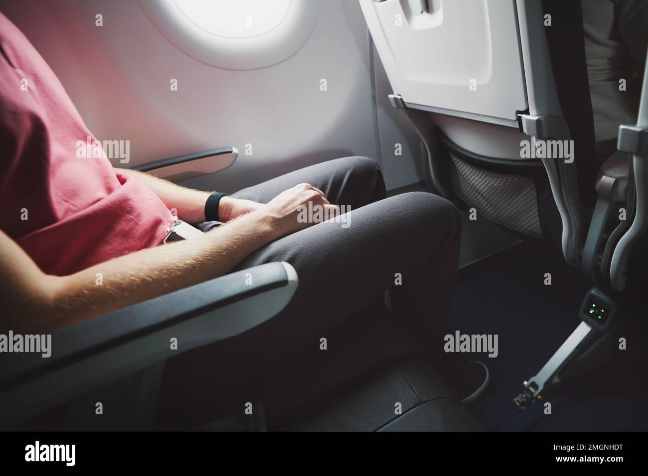 Man resting during flight. Legroom between seats in commercial airplane. Stock Photo